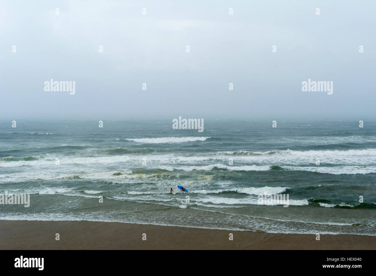 Una coppia di donne andare il surf in un robusto e tempestoso oceano. Foto Stock