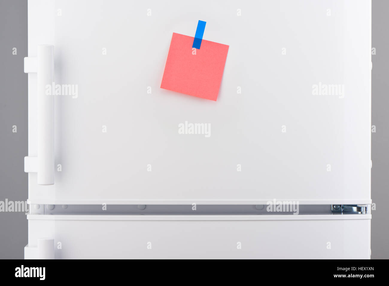 Vuoto carta rosa nota allegata con adesivo blu su bianco porta di frigorifero Foto Stock