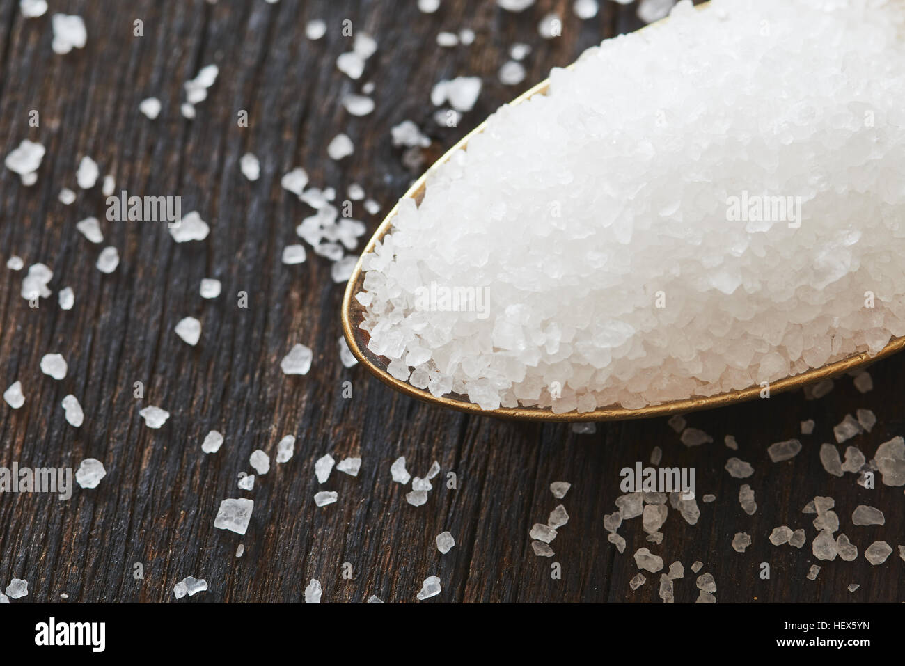 Il sale di mare in un cucchiaio sul tavolo di legno Foto Stock