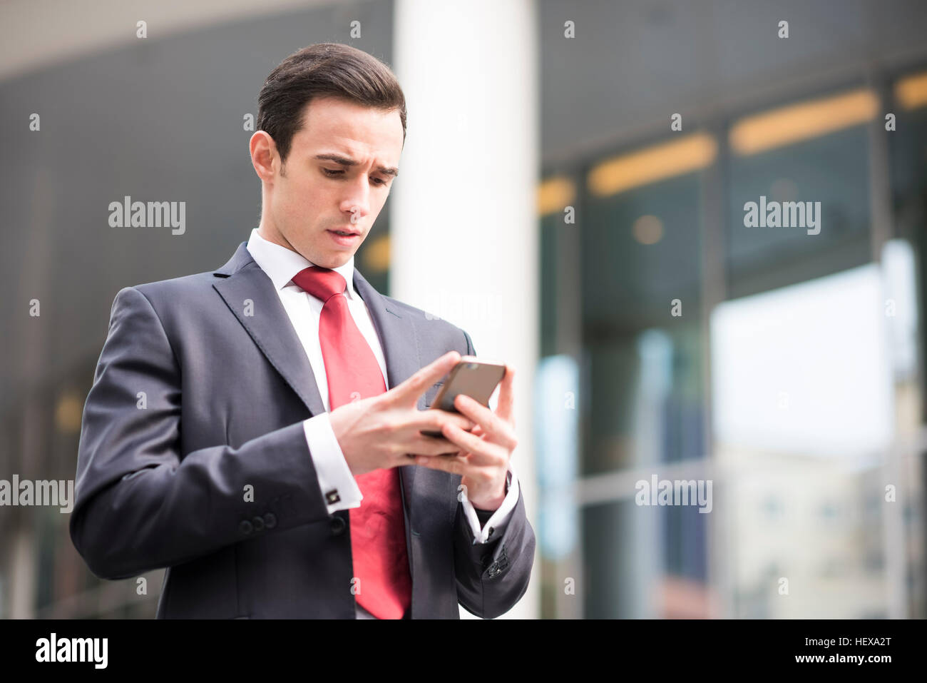 Uomo d'affari in città guardando smartphone Foto Stock