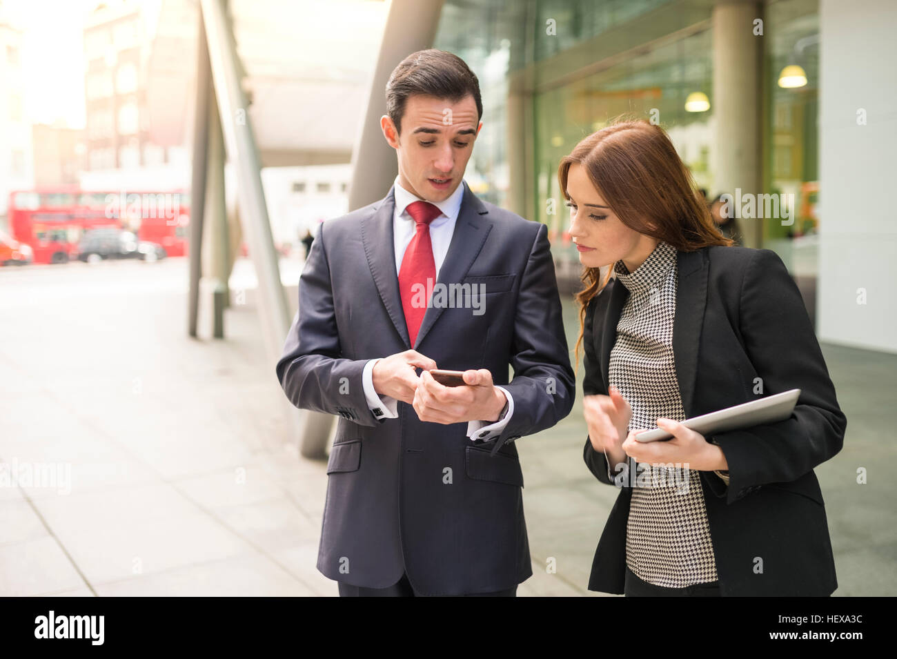 Gli imprenditori in città guardando a parlare dello smartphone Foto Stock