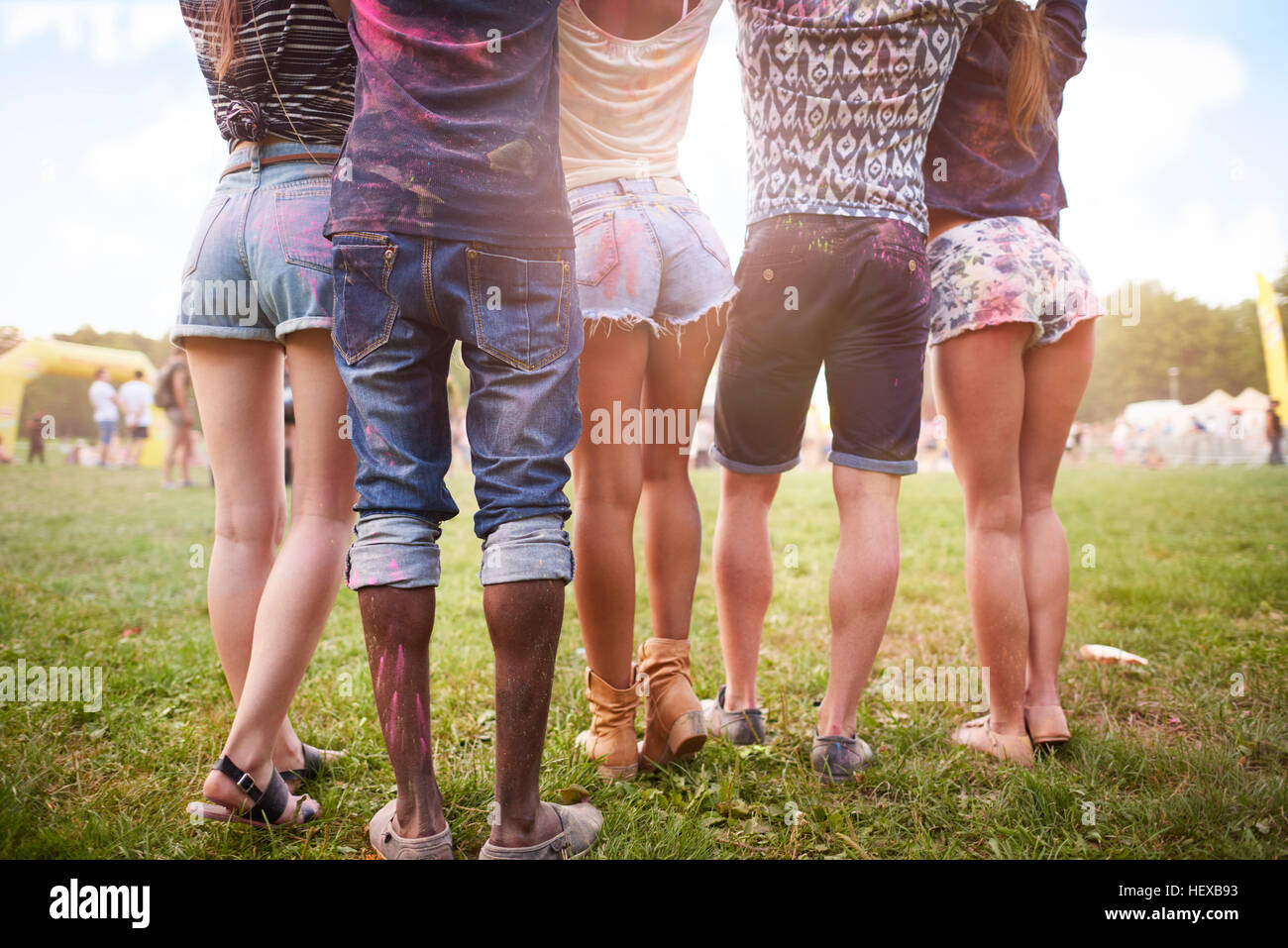 Gruppo di amici al festival, coperto di polvere colorata vernice, bassa sezione, vista posteriore Foto Stock