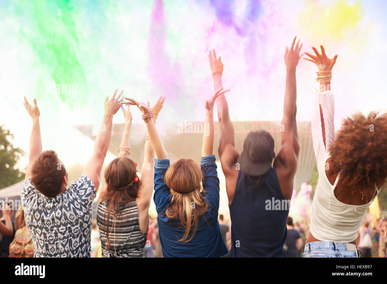 Gruppo di amici al festival, gettando colorati di vernice in polvere in aria, vista posteriore Foto Stock