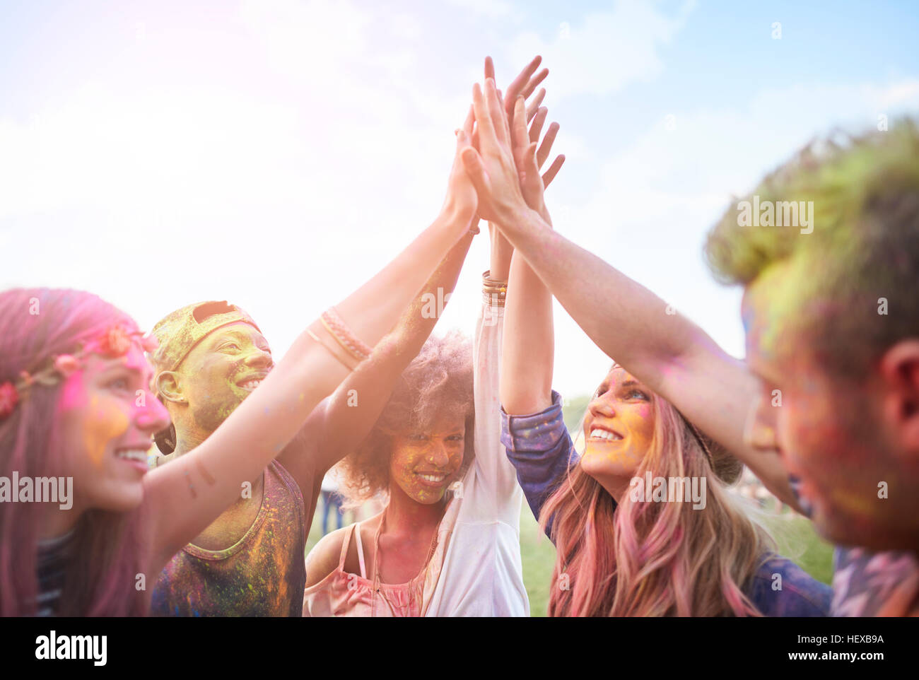 Gruppo di amici al festival, coperto di polvere colorata vernice, unendo le mani Foto Stock