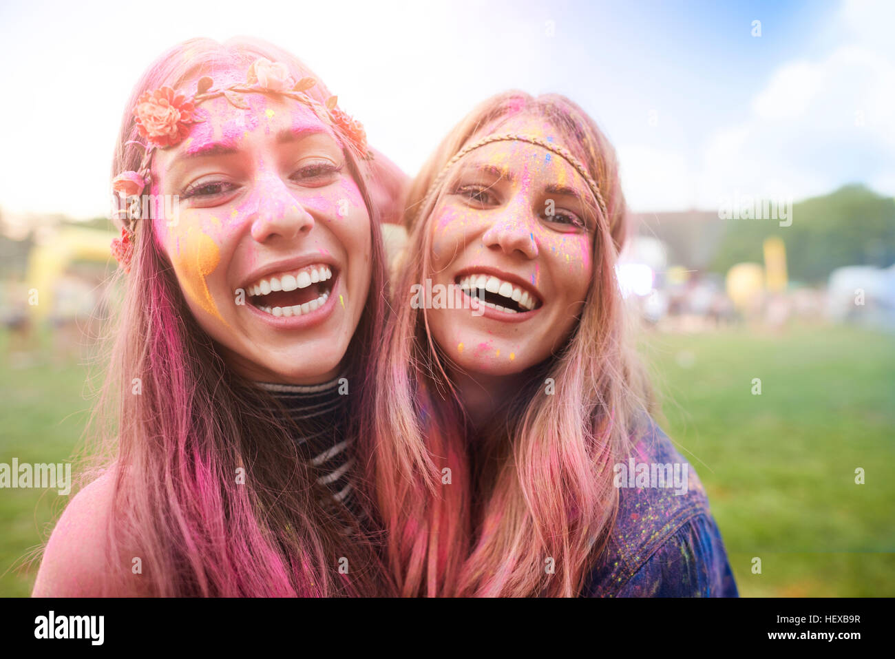 Ritratto di due amici di sesso femminile al festival, coperto di polvere colorata vernice Foto Stock