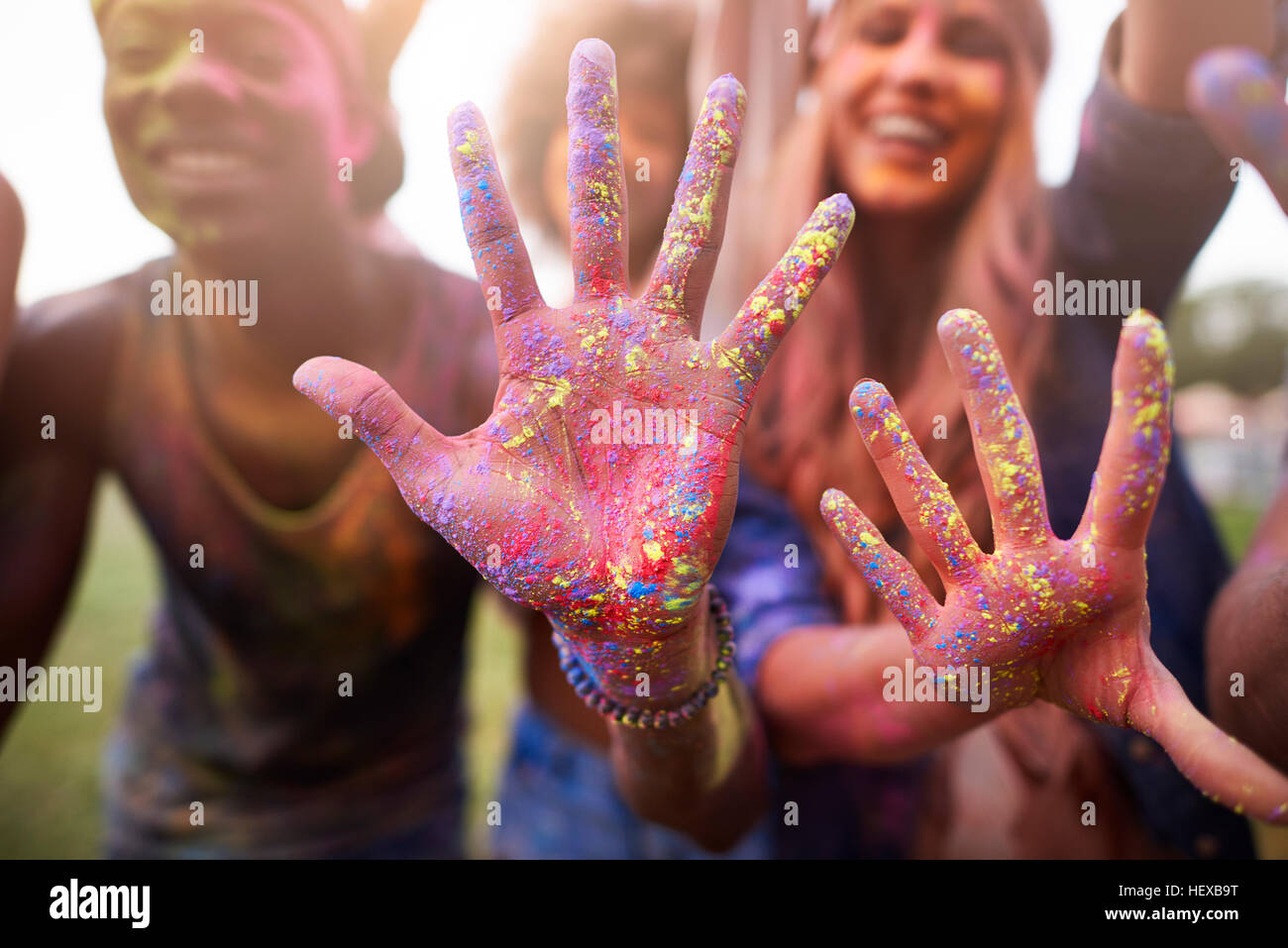 Gruppo di amici al festival, coperto di polvere colorata vernice Foto Stock