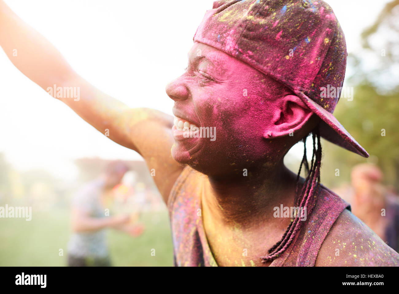 Giovane uomo al festival, coperto di polvere colorata vernice, bracci sollevati, dancing Foto Stock