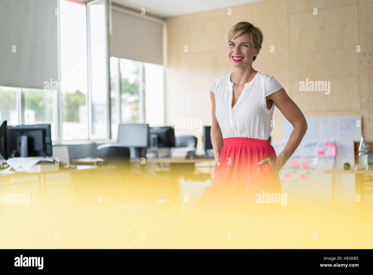 Donna sorridente in piedi in ufficio creativo Foto Stock
