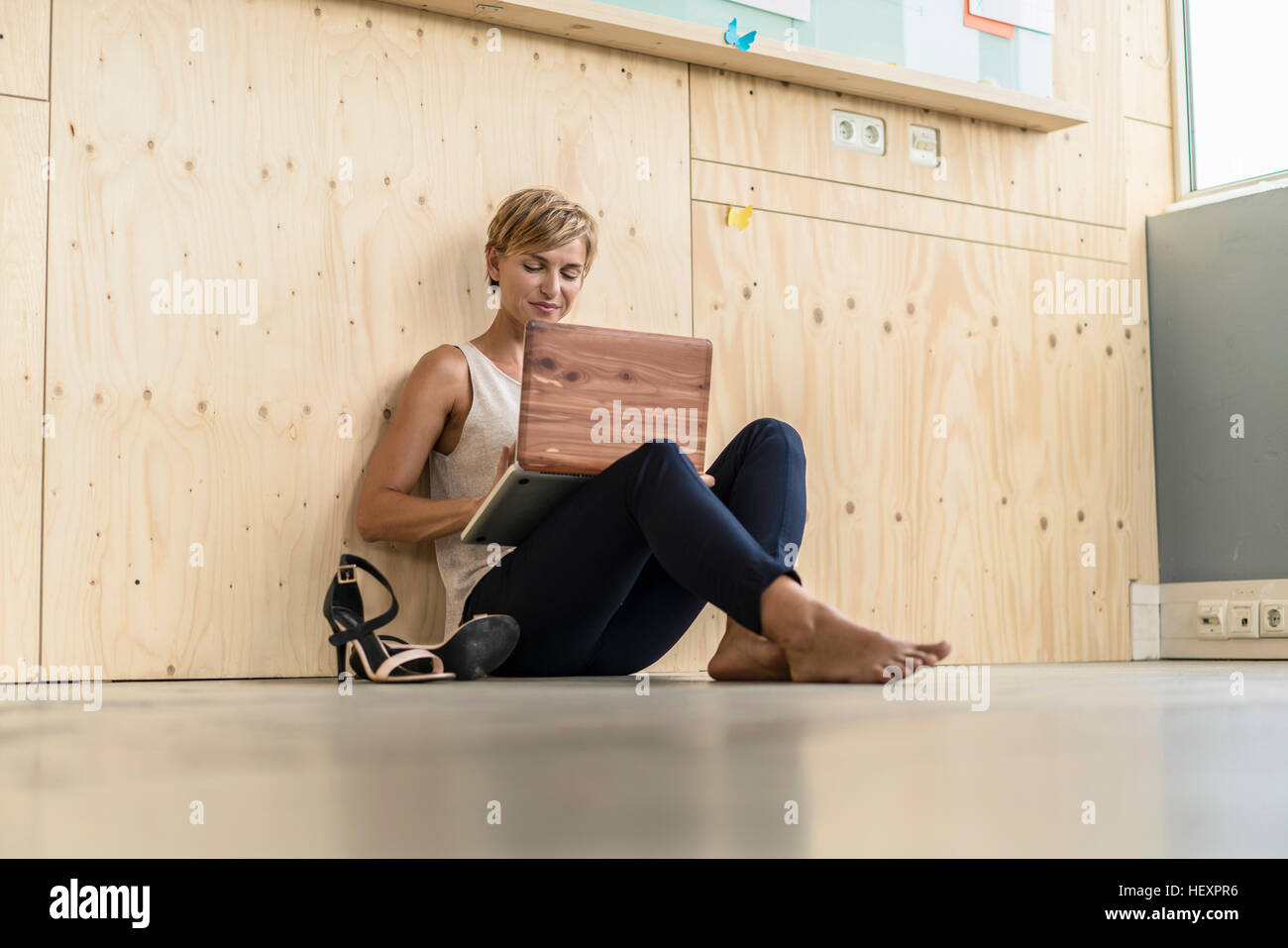 Imprenditrice utilizzando laptop sul pavimento Foto Stock