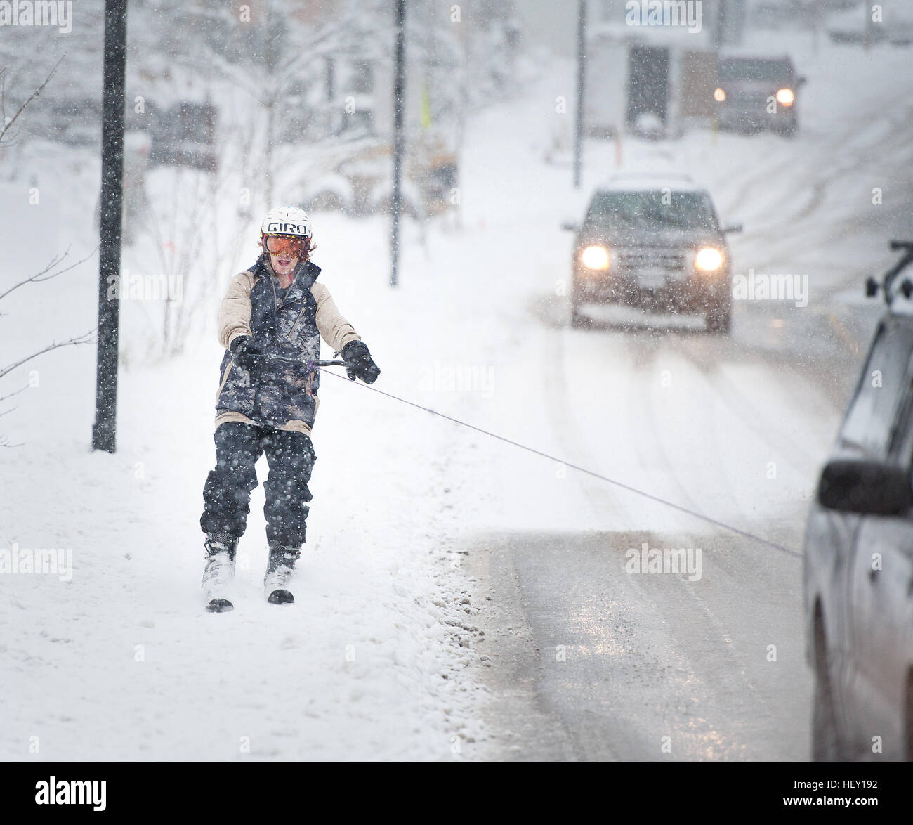 Un uomo ottiene un rimorchio per sci dietro un camion fino a strada durante una tempesta di neve invernale blizzard. Squamish BC, Canada divertimento sciistico durante una tempesta di neve in inverno. Foto Stock