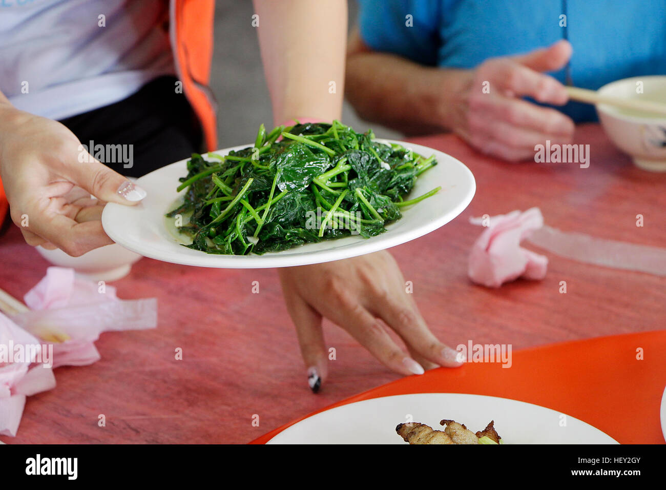 Piatto di verdure a foglia verde essendo servita da donna. Foto Stock