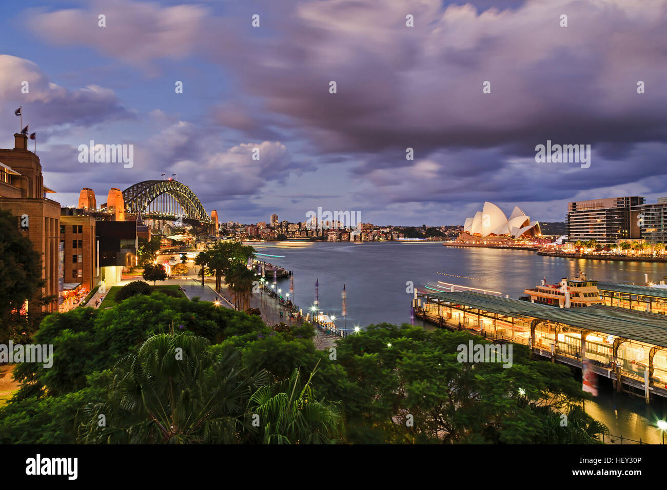 Il Ponte del Porto di Sydney e Circular Quay traghetti passeggeri dal terminale di elevazione al di sopra di verde e di alberi che circondano i punti di riferimento Foto Stock