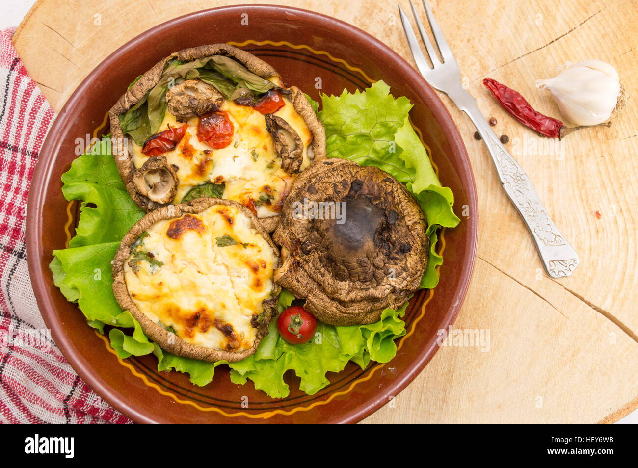 Uovo Funghi ripieni su una piastra di colore marrone con pomodori ciliegia Foto Stock