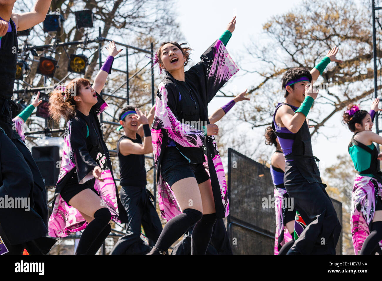 Yosakoi giapponese festival. Il team di danza sul palco, principalmente in costume nero danzando e cantando, bracci sollevati sopra le loro teste. Esterno, giorno. Foto Stock