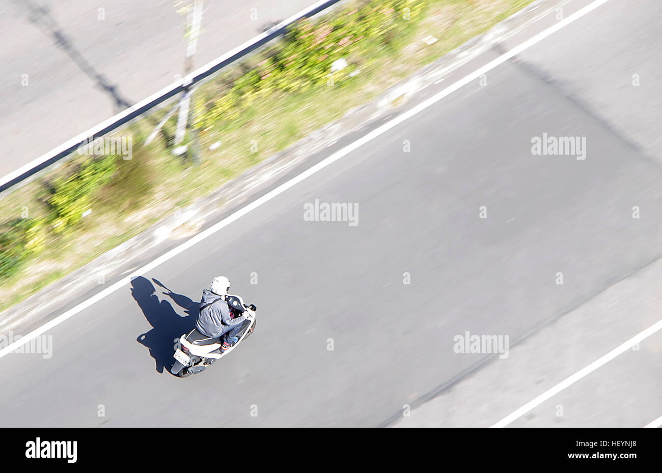 Uomo su scooter guida veloce su strada Foto Stock