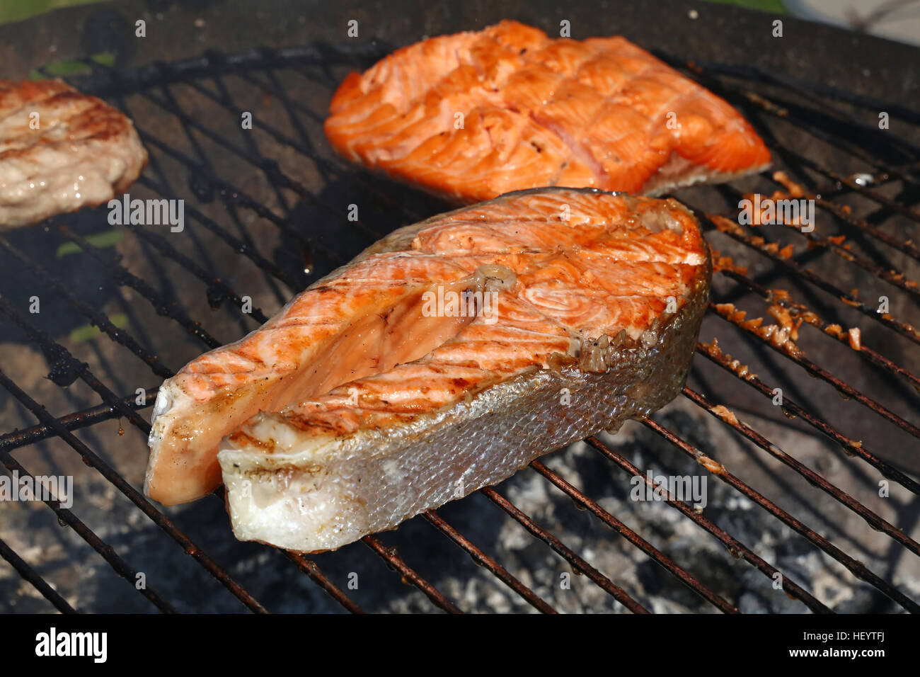 Una grigliata di pesce Salmone bistecca pasto barbecue per la cottura, preparato sulla griglia per il barbecue, close up Foto Stock