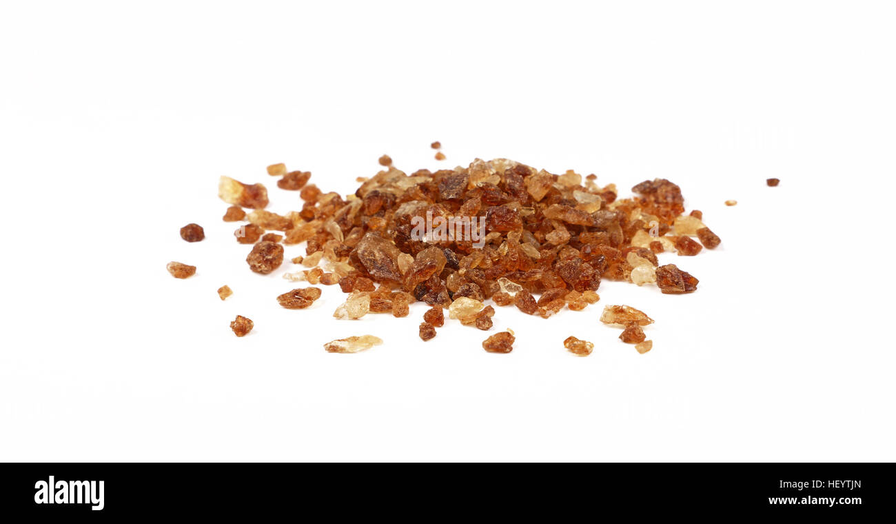 Pizzico di big brown caramella di cristalli di zucchero versato intorno isolato su sfondo bianco, vicino fino a basso angolo di visione Foto Stock