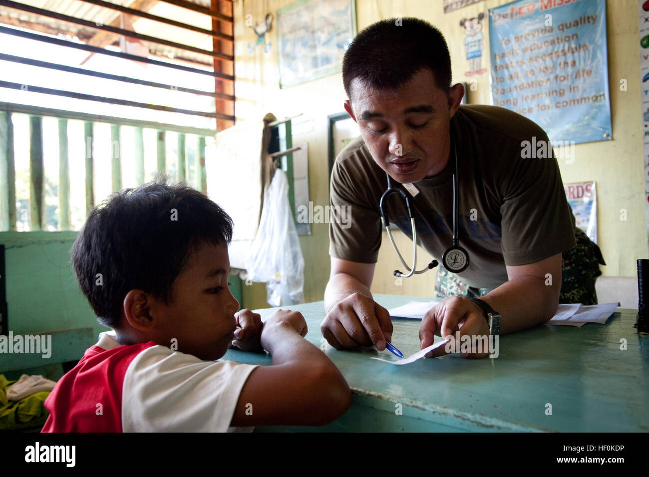 Philippine Marine Capt. Sangoy Juland spiega la prescrizione è di dare ad un ragazzo a Quinlogan Scuola Elementare, PALAWAN FILIPPINE, Ottobre 23, 2011. I medici e dentisti azione civile progetto era in Philbex 2012 e fu destinato ad aiutare il filippino e U.S. forze armate" la capacità di reagire rapidamente e di lavorare insieme per fornire soccorso e di assistenza in caso di calamità naturali e di altre crisi che minacciano la sicurezza e la sanità pubblica. (U.S. Marine Corps foto di Cpl. Patricia D. Lockhart/RILASCIATO) Philippine Marine Capt. Sangoy Juland spiega la prescrizione è di dare ad un ragazzo Foto Stock