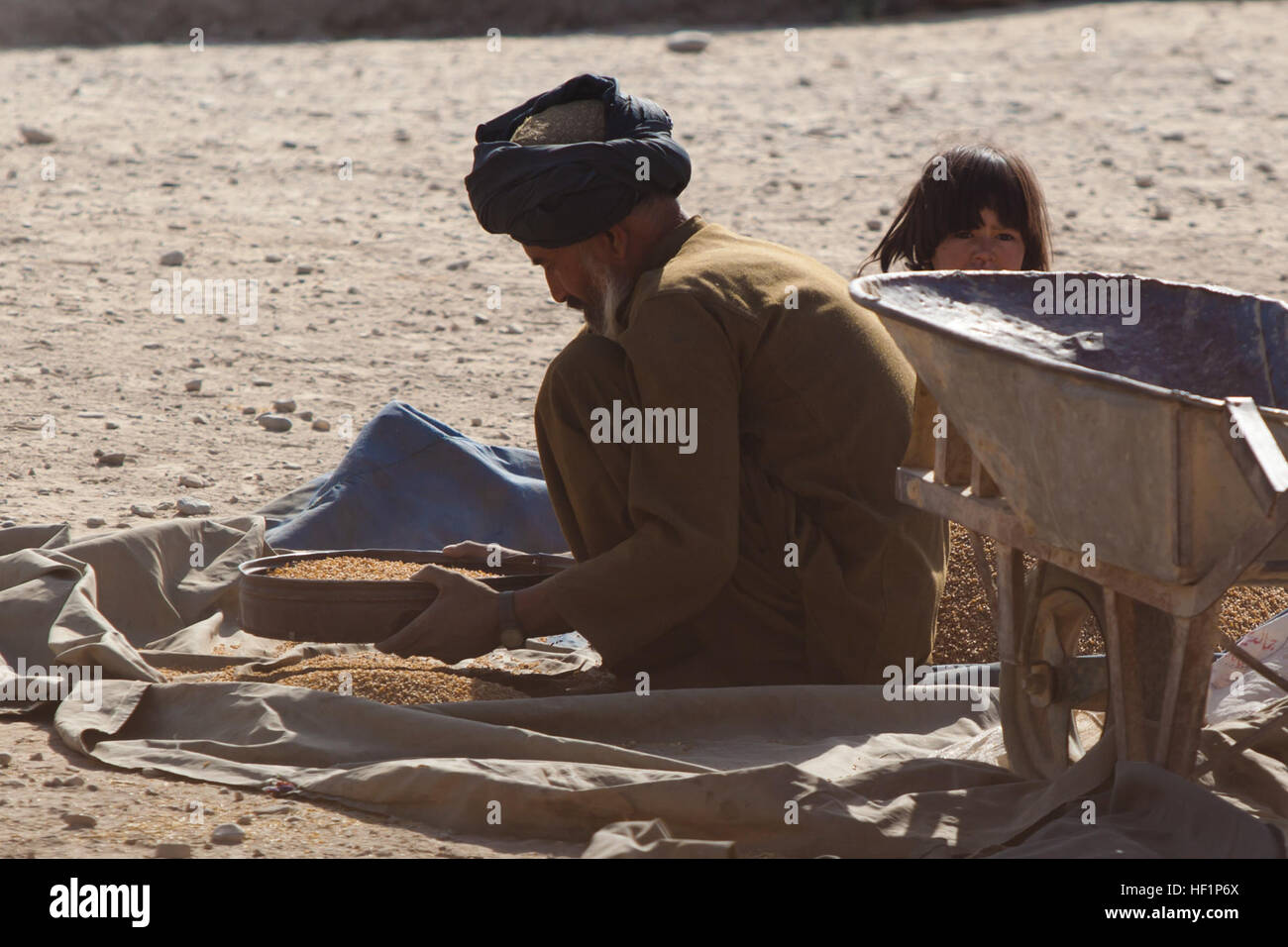 Un maschio Afghano setaccia attraverso il grano in Musa Qala, provincia di Helmand, Afghanistan, Ottobre 22, 2013. Alimenti e recentemente raccolti sono un sito comune in tutta la zona come gli agricoltori locali regnare nei loro beni. (U.S. Marine Corps foto di Cpl. Paul Peterson) vagliatura 131022 granella-M-ZB219-214 Foto Stock