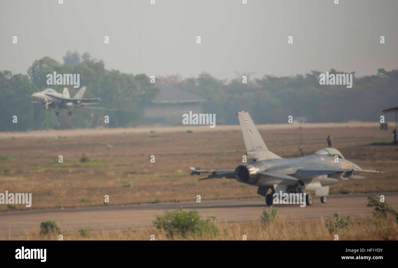 Un FA-18D Hornet aereo decolla come un Thai F-16 attende di decollare da una ala Royal Thai Air Force Base, Nakhon Ratchasima, Regno di Thailandia, Feb. 19 durante l'esercizio Cobra Gold 2014. CG 14 è un giunto, multinazionale esercizio condotte annualmente nel Regno di Thailandia volti a migliorare e incrementare l'interoperabilità multinazionale. Il FA-18D Hornet è con Marine Tutti Meteo attacco Fighter Squadron 242, Marine Aircraft Group 12, 1° Marine ala di aereo III Marine Expeditionary Force. La F-16 è con lo squadrone 103, Ala, Royal Thai Air Force. (U.S. Marine Corps foto di Cpl. Ja Foto Stock