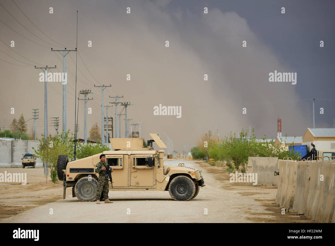 Un esercito nazionale afgano soldato, assegnato alla 215th Corps, sorge accanto a un ANA Humvee proteggendo allo stesso tempo il coordinamento operativo Centro- regionali (OCC-R) durante l'Afghanistan elezioni presidenziali, come una tempesta di sabbia si avvicina a bordo campo Shorabak, provincia di Helmand, Afghanistan, 5 aprile 2014. Il 1393 (2014) le elezioni presidenziali è il primo anno di forze di sicurezza nazionali afgane (ANSF) hanno preso il filo per un tale evento. (Ufficiale DEGLI STATI UNITI Marine Corps photo by Lance Cpl. Darien J. Bjorndal, Marine Expeditionary Brigade Afghanistan/ Rilasciato) ANSF nella provincia di Helmand durante 2014 Electi Foto Stock