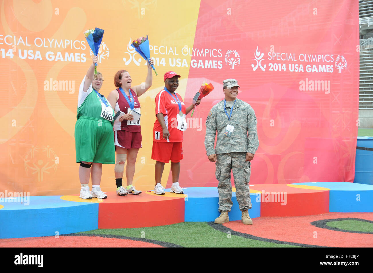 Stati Uniti Il personale dell'esercito Sgt. Jose Gomez con il New Jersey Air National Guard delle 253 società di trasporti, pause per una foto con gli atleti che partecipano al Mini giavellotto 300gr donne della divisione Giugno 19, 2014. (U.S. Air National Guard foto di Airman Ambra Powell/RILASCIATO) New Jersey Guardia Nazionale supporta Special Olympics 140616-Z-PJ006-056 Foto Stock