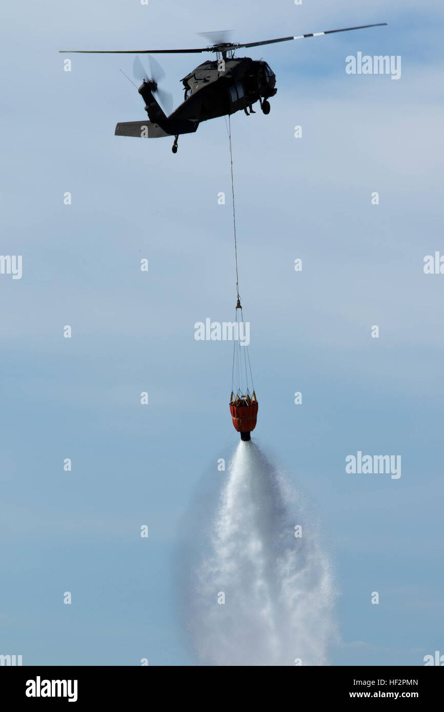 Tre-cento-e-Cinquanta galloni di acqua cadere nel cielo da un Bambi cucchiaio sospeso 50 piedi sotto un esercito di Arizona Guardia Nazionale UH-60 Black Hawk elicottero appartenente a una società, 2-285th elicottero d'assalto battaglione di stanza a Phoenix, Dic 12, 2014, a Rittenhouse Eliporto dell esercito in Queen Creek, Ariz. Tre UH-60 i falchi nero e diversi equipaggi dal 2-285th AHB trascorso la mattinata a prelevare acqua da un canale e lasciandolo cadere su bersagli durante la wildland annuale di formazione antincendio. (U.S. Esercito nazionale Guard photo by Staff Sgt. Brian A. Barbour) Arizona treni di guardia alla lotta wildl Foto Stock