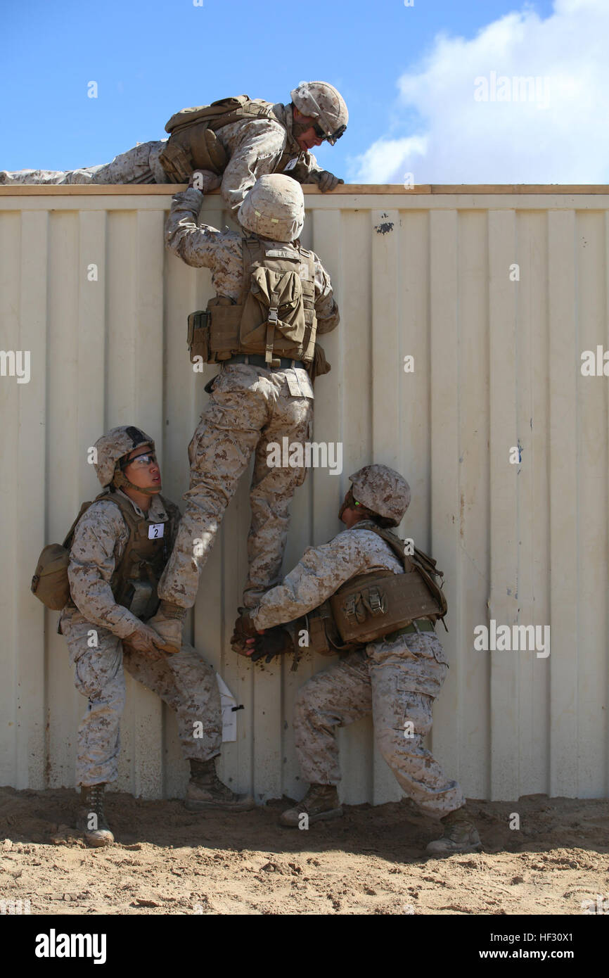 Sergenti Emma A. Bringas, sinistra e Amaya Marin Garnica, a destra il sollevamento della lancia Cpl. Terrence A. laico, anti-serbatoio missileman con sezione Anti-Armor, armi Company, il combattimento a terra integrati elemento Task Force, oltre ad otto piedi parete ostacolo durante un test pilota a gamma 107, Marine Corps Air Ground Centro di combattimento ventinove Palms, California, il 2 marzo 2015, in preparazione per il Marine Corps Prova di funzionamento e di attività di valutazione Valutazione. Da ottobre 2014 a luglio 2015, il GCEITF sarà condotta individuale e collettivo di competenze di livello di formazione in massa designato combat arms speci professionali Foto Stock
