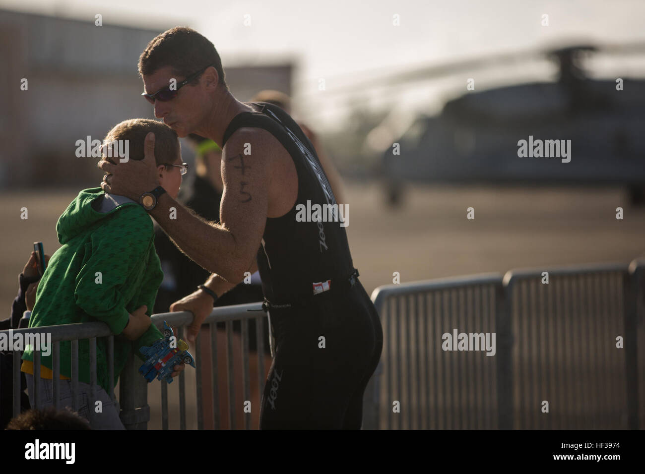 Michael McMillen bacia il suo figlio sulla fronte prima di iniziare l'esecuzione di parte di Koa Kai Triathlon Sprint a bordo Marine Corps Air Station Kaneohe Bay, 3 maggio 2015. Il triatheletes ha iniziato la concorrenza con una 500 m nuotare nella Baia di Kaneohe seguita da un frenetico 11.1-miglio in bicicletta intorno alla linea di volo, terminando con un 5K run che ha terminato a Hangar 103. (U.S. Marine Corps foto di Cpl. Brittney Vella/RILASCIATO) Triatleti competere a MCAS K-Bay 150503-M-TM809-008 Foto Stock