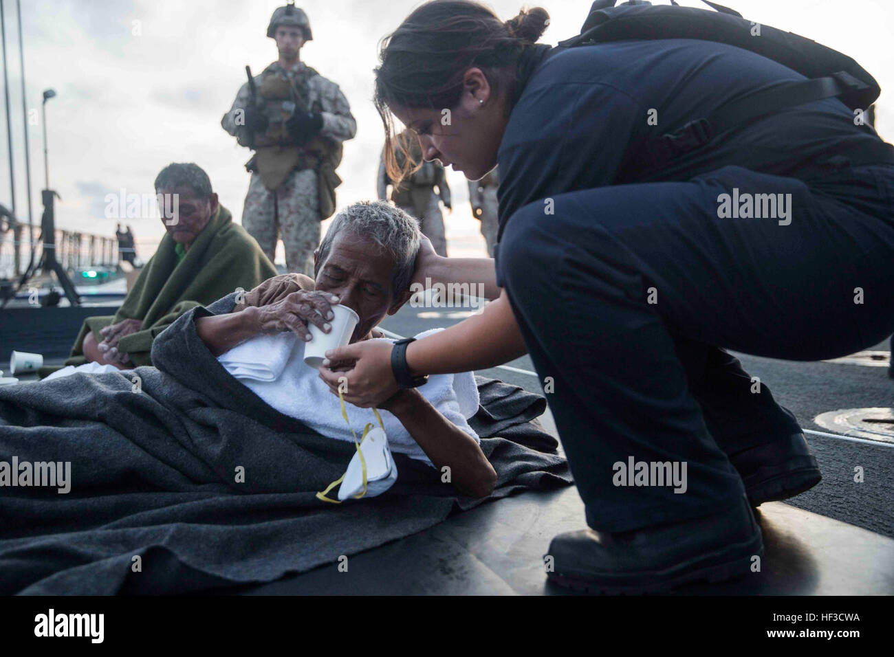 Un U.S. Navy Sailor fornisce acqua a un distressed mariner a bordo della USS Rushmore (LSD 47) in mare Stretto di Makassar, 10 giugno 2015. Rushmore resi assistenza al distressed marittimi nelle acque tra le isole indonesiane di Kalimantan e Sulawesi. Una volta a bordo, gli sfollati sono stati forniti cibo e cure mediche da marines e marinai del XV Marine Expeditionary Unit ed Essex anfibio gruppo pronto. (U.S. Marine Corps foto di Sgt. Emmanuel Ramos/RILASCIATO) 65 indonesiani salvato dalla tragedia di U.S. Marines, marinai 150610-M-ST621-474 Foto Stock
