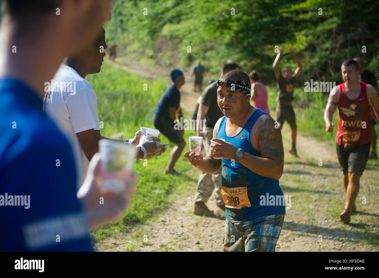 Un partecipante di eseguire annuale insano, ospitato dalla Marine Corps Marathon (MCM), riceve l'acqua da un volontario a Marine Corps base Quantico, Va., 13 giugno 2015. Il Run insano è il MCM messiest del fango e la corsa a ostacoli costituiti da una a quattro chilometri di sentiero con 21 sfide per includere una trincea di fango, crawl bassa e un pozzo del fango. L'evento comprendeva anche una scalata due-miglio versione del corso, il Mini eseguire insano. (U.S. Marine Corps photo by Lance Cpl. Terry W. Miller Jr./RILASCIATO) Eseguire Amuk 150613-M-RU287-0594 Foto Stock