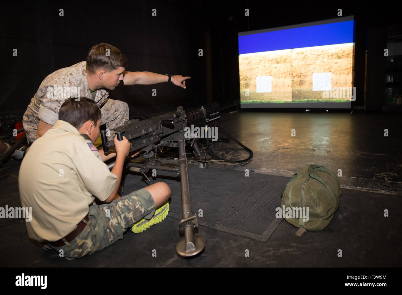 Lancia Cpl. Christopher Bailey, assaultman, 3° Battaglione, 7° Reggimento Marine, dirige il fuoco come Devin Castanon, 12, boy scout, truppa 72, si prepara a fuoco un M240B Mitragliatrice all'interno simulato precisione di tiro Trainer durante il Boy Scout Camp per local Boy Scouts of America truppe Marzo 18, 2016. (Gazzetta Marine Corps foto di Sgt. Charles Santamaria/RILASCIATO) Boy Scout giornata esperienza nella vita 160318-M-YE994-463 Foto Stock