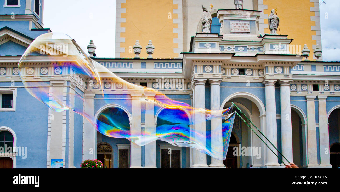 Grande bolla di sapone con mille riflessi colorati creati da un giocoliere per rendere i bambini felici per il Duomo di Bressanone sfondo Foto Stock