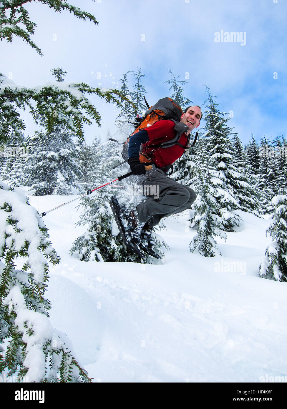 Un uomo divertirsi saltando attraverso gli alberi con le racchette da neve Foto Stock