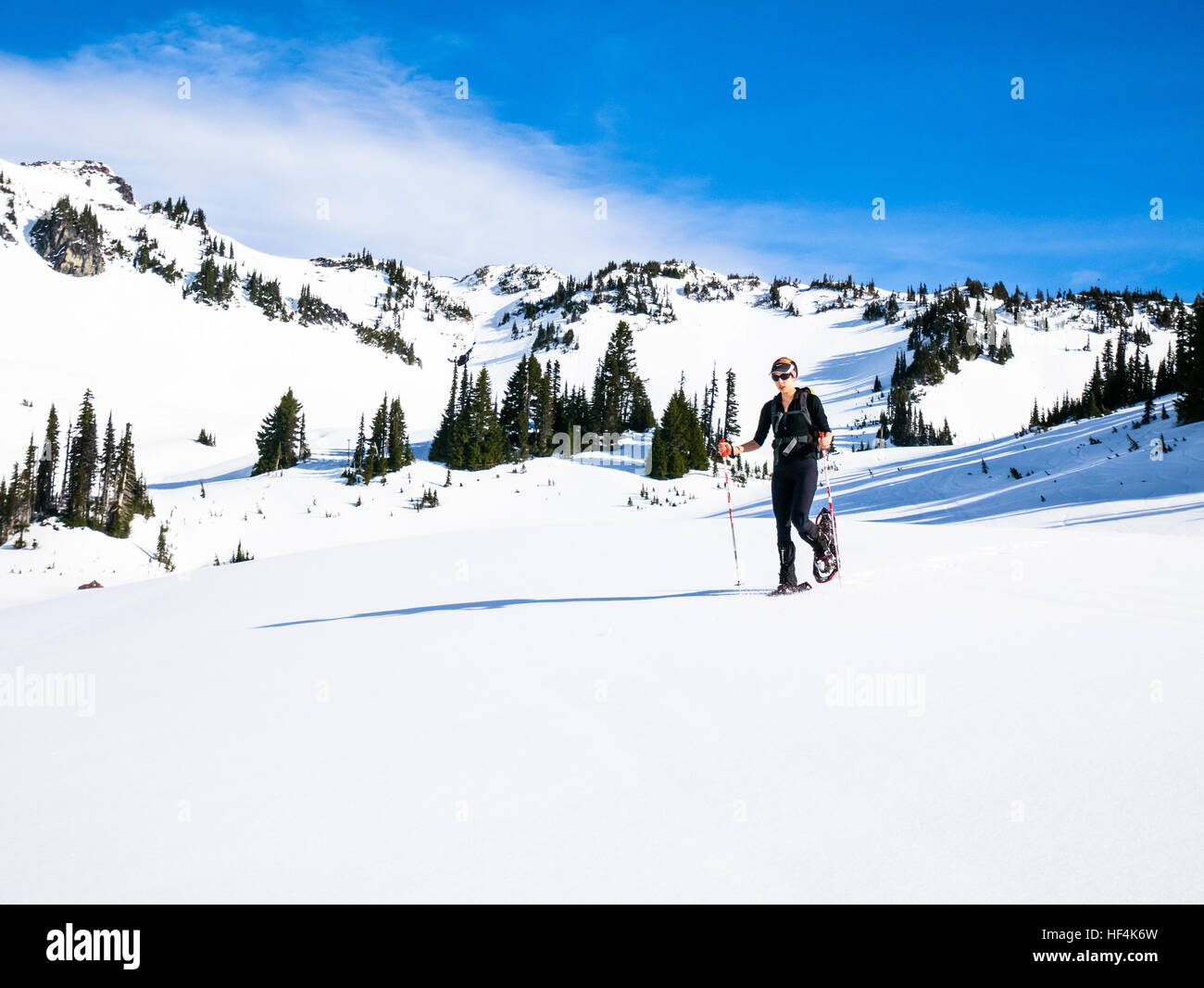 Una giovane donna con le racchette da neve nelle montagne del Monte (Mt) Rainier National Park Foto Stock