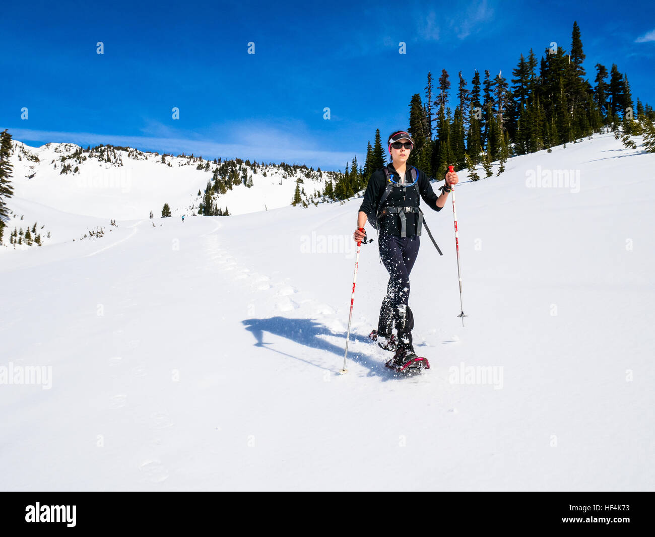 Una giovane donna con le racchette da neve nelle montagne del Monte (Mt) Rainier National Park Foto Stock