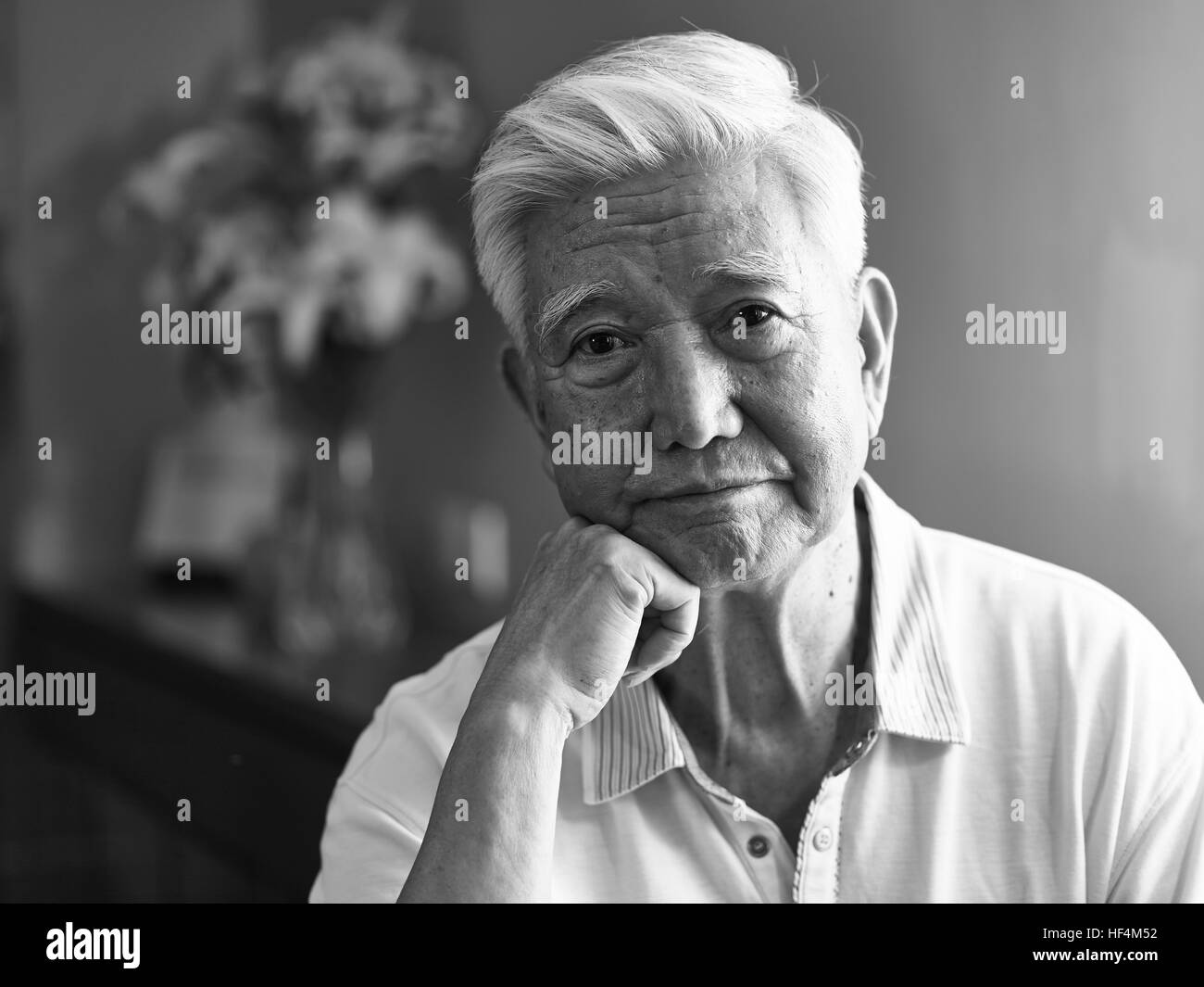 Ritratto in bianco e nero di un triste lonely asian senior mano sul mento guardando la fotocamera. Foto Stock