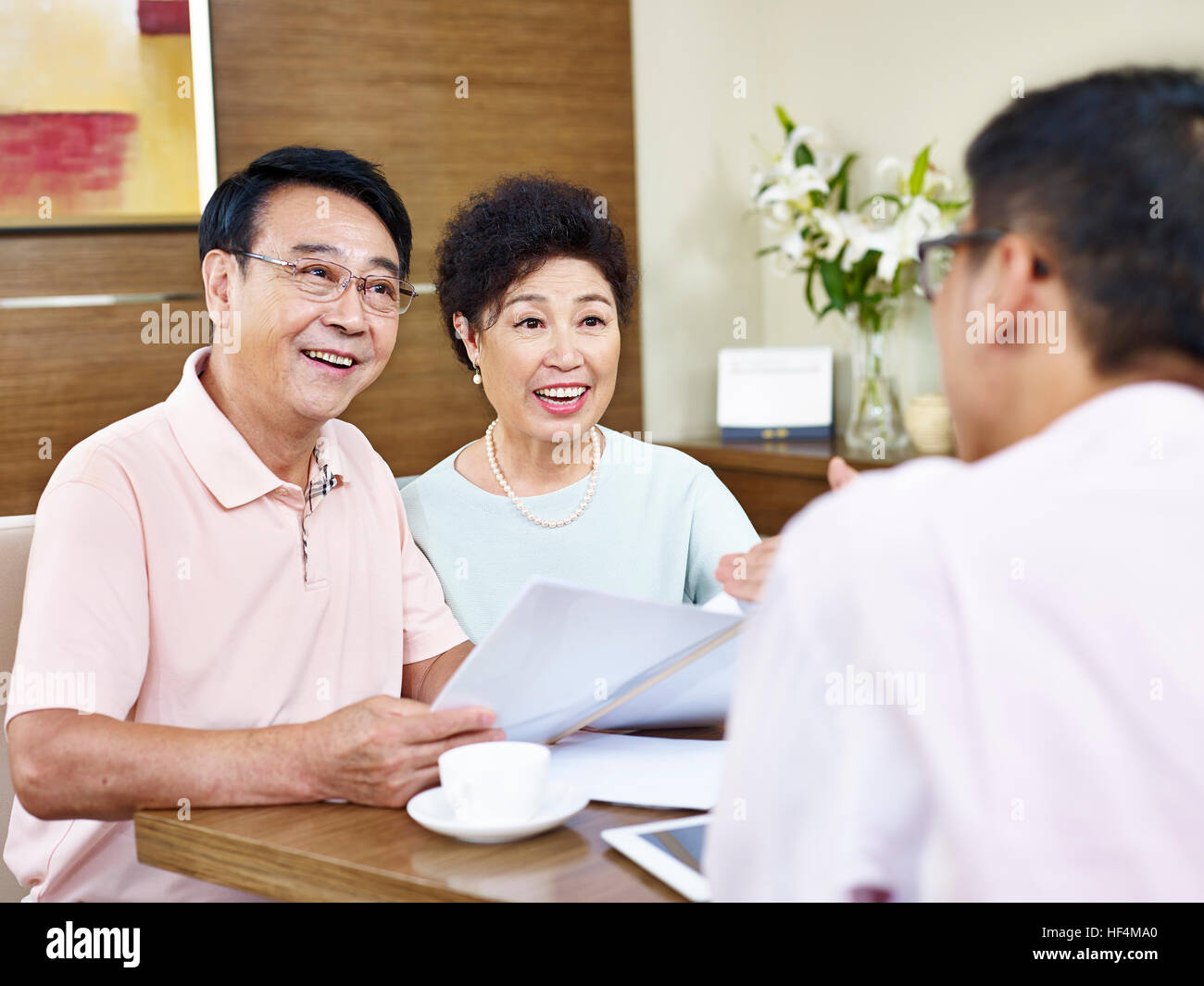Senior asian giovane ascoltare la spiegazione da parte di un rappresentante di vendita, felice e sorridente. Foto Stock