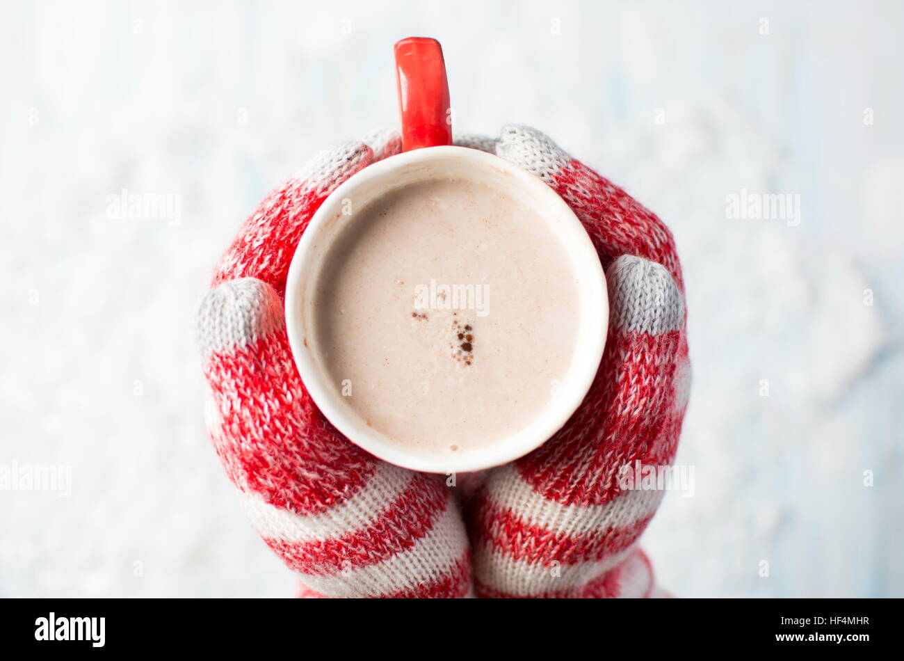 Mani femminili in azienda guanti cioccolato caldo su un sfondo innevato Foto Stock