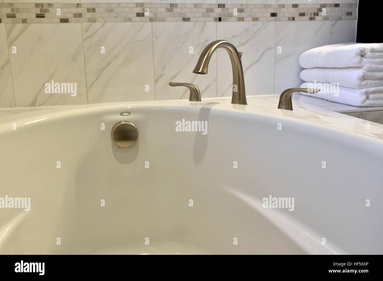 Stanza da bagno in marmo bianco con asciugamani posa accanto alla vasca Foto Stock