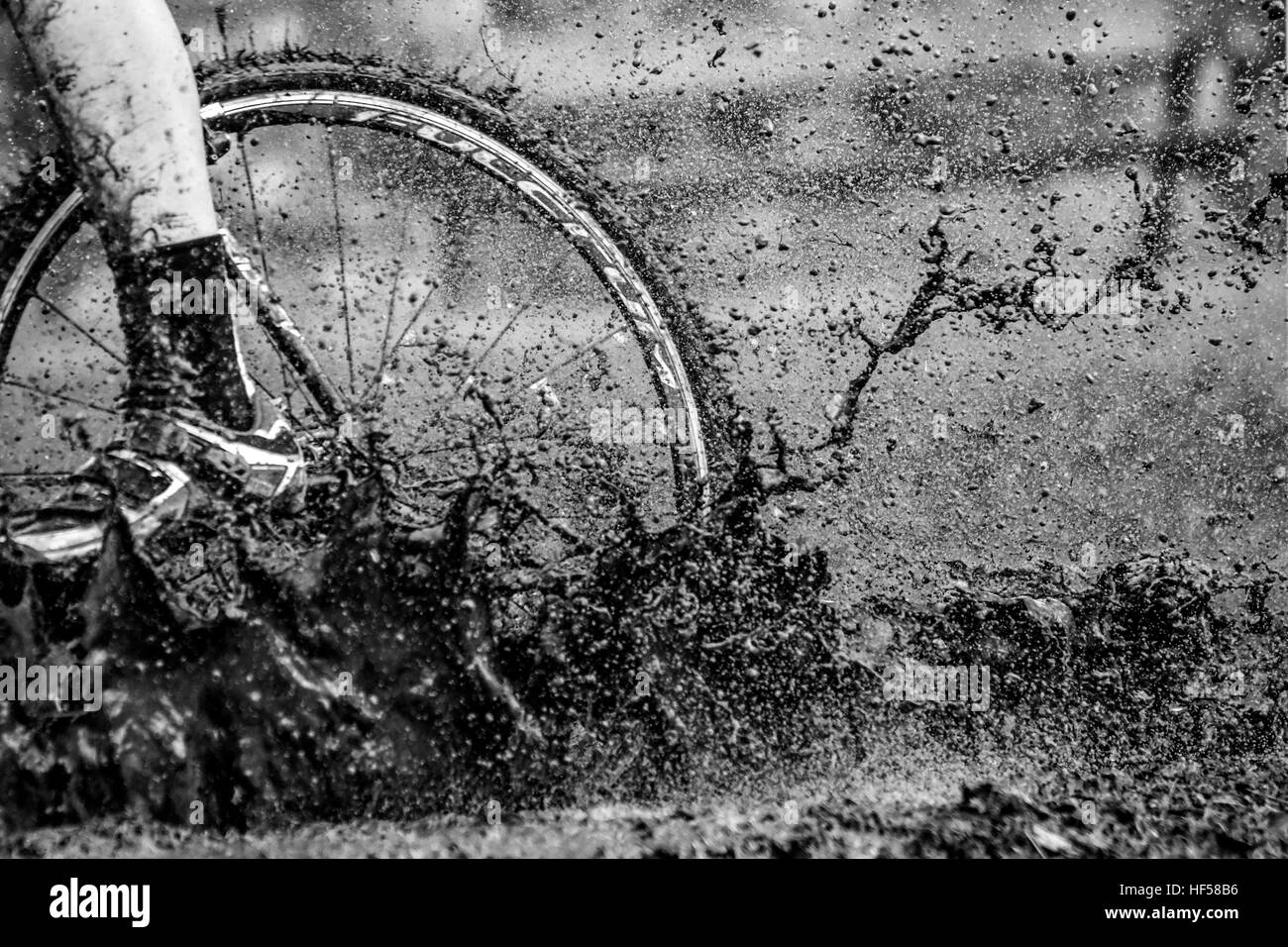 La ruota di un ciclista su una pozzanghera schizzi di fango accumulato durante il 2016 Ciclo-Cross di Gijon si celebra in Spagna. Foto Stock