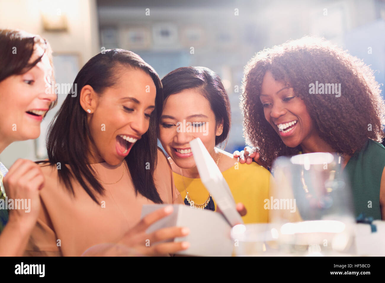 Gli amici a guardare la donna aprire regalo di compleanno Foto Stock