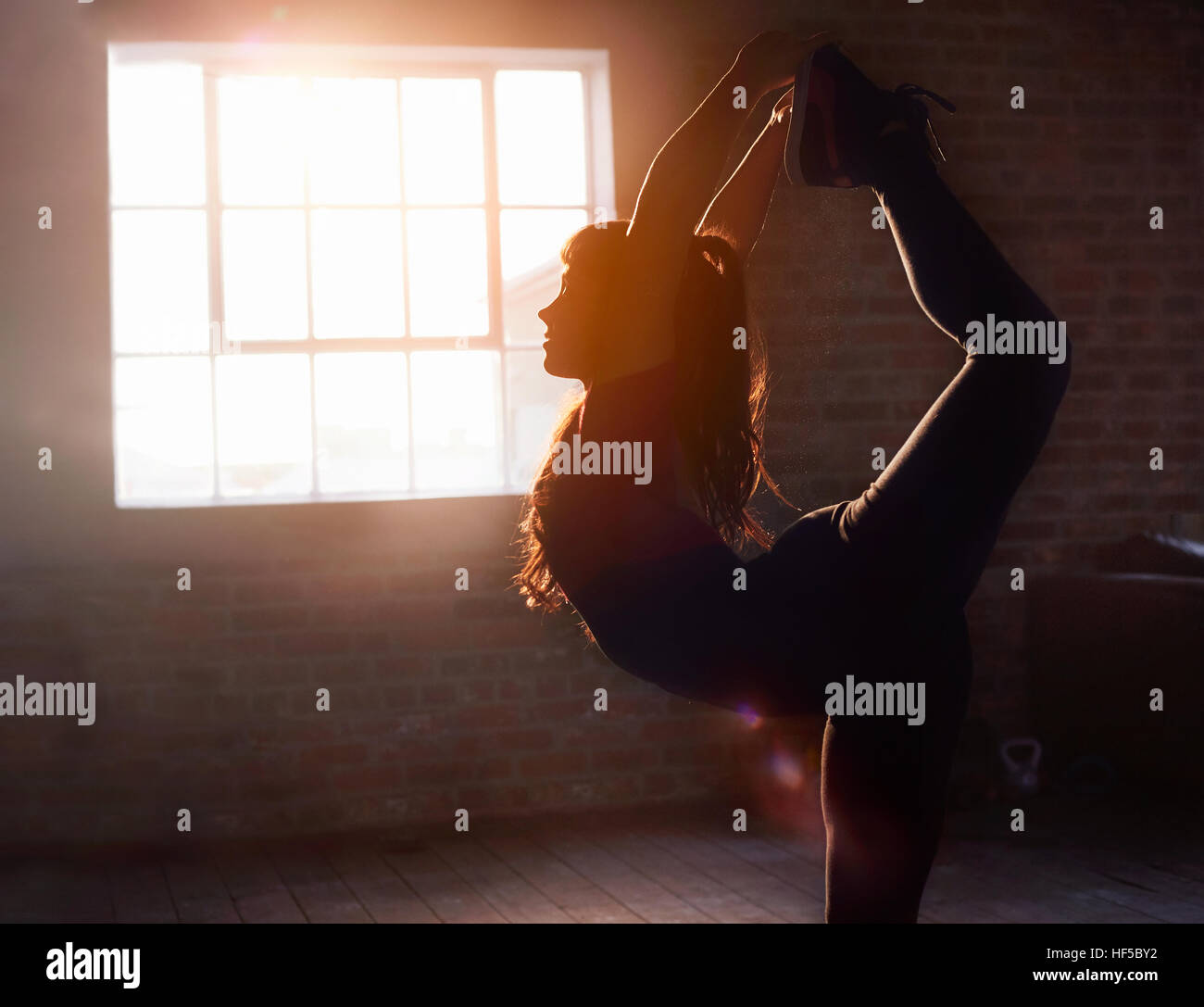 Silhouette ballerino femmina stretching a praticare yoga re posizione del signore della danza in studio Foto Stock