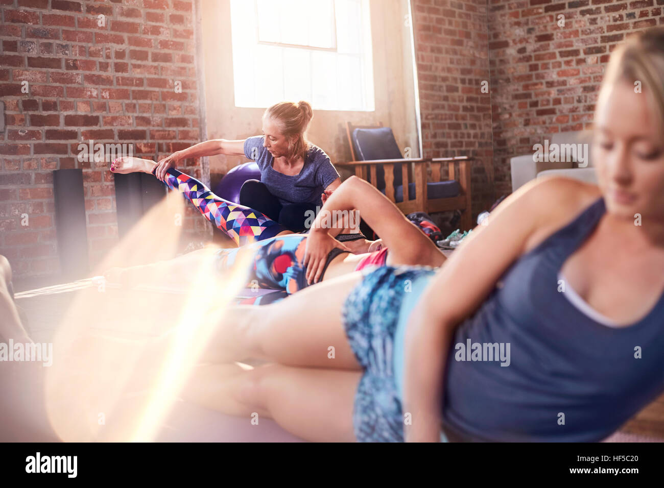 Istruttore di Fitness aiutando giovane donna pratica lato Plank in palestra studio Foto Stock