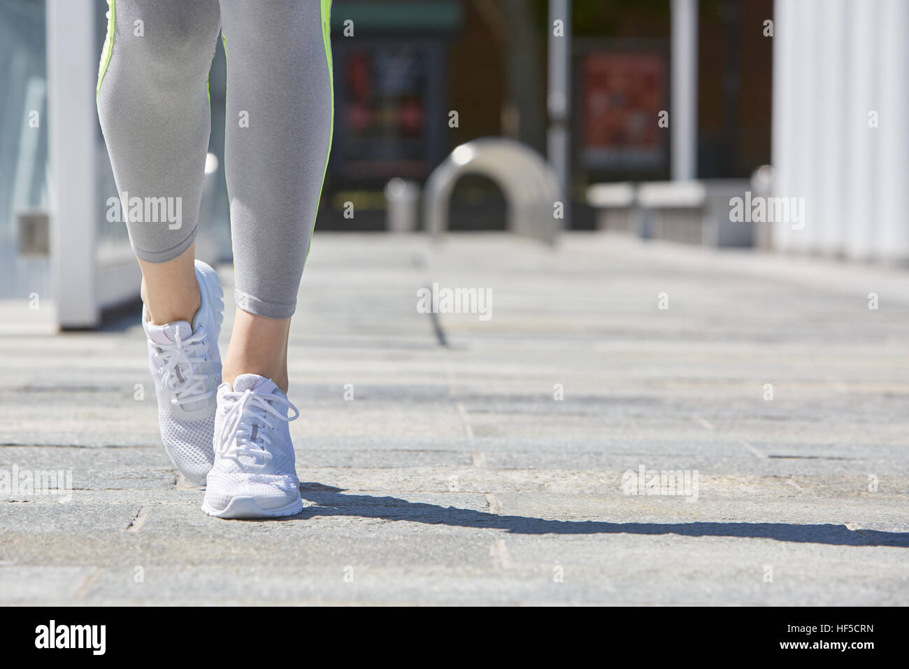 Donna con scarpe da ginnastica e tuta in città in estate Foto Stock