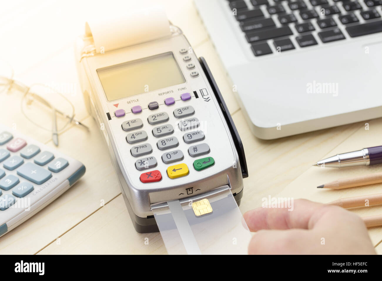 Cassiere effettuato un pagamento in negozio via EDC o terminale carte di credito con computer laptop, calcolatrice, penna e matita. Foto Stock