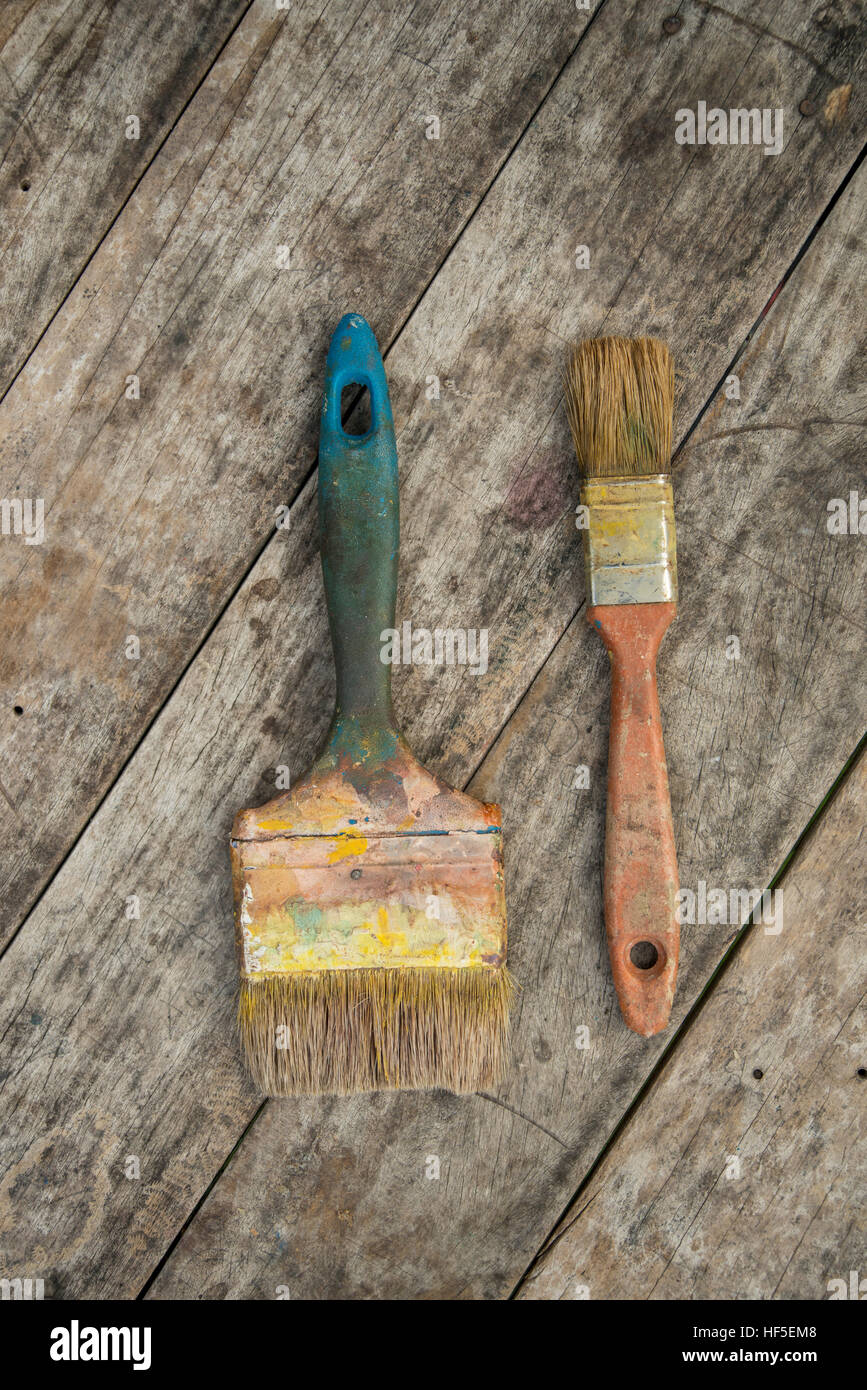 Coppia di spazzole usate con i bit di vernice essiccata su uno sfondo di legno Foto Stock