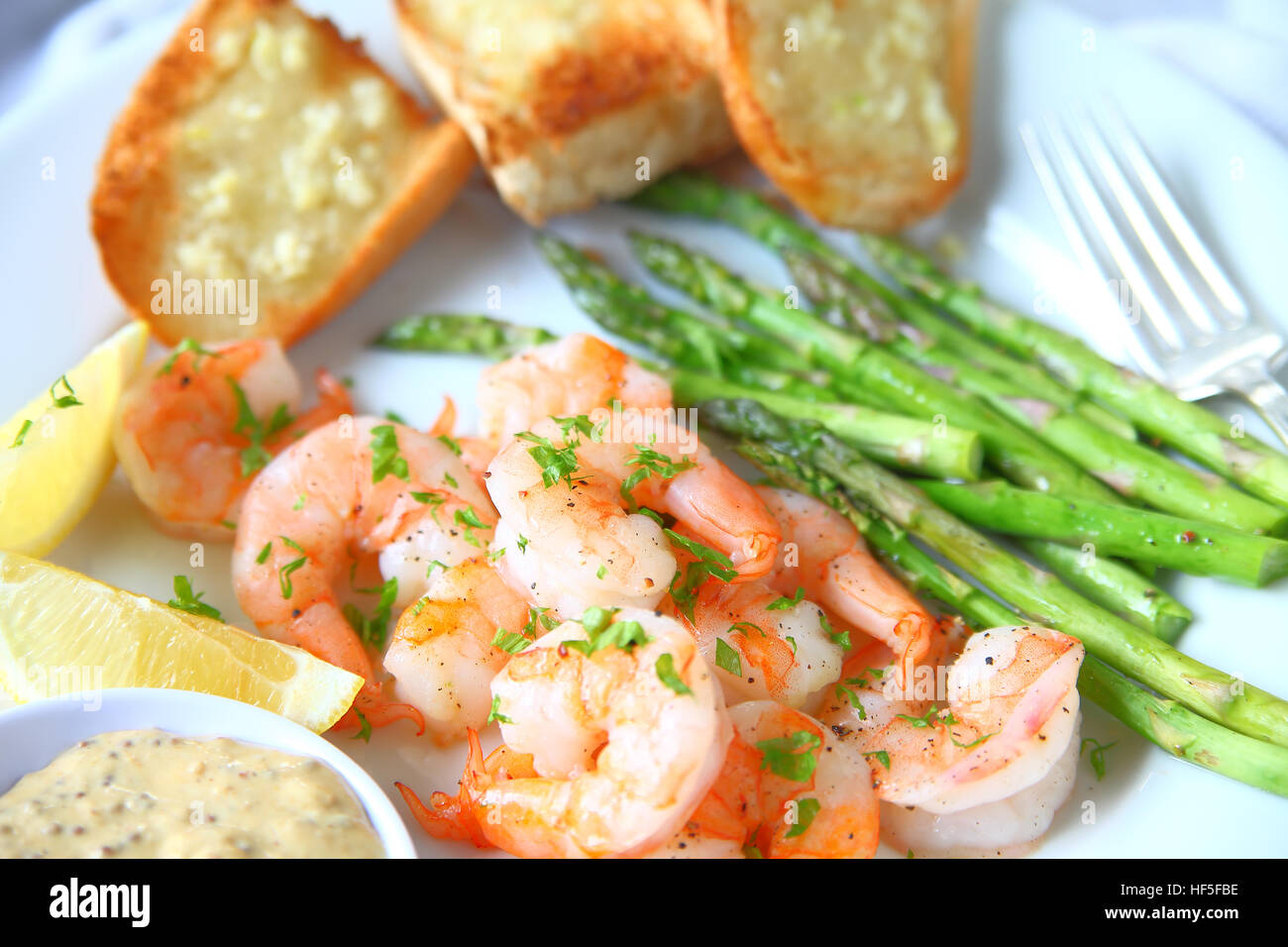 Piatto di arrosto di gamberi e asparagi con aglio pane, succo di limone e la salsa di senape Foto Stock