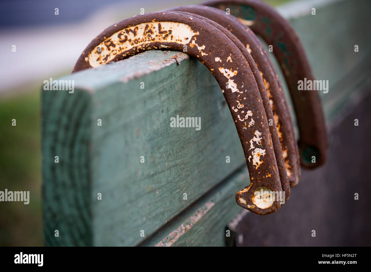 Rusty, vecchi Ferri da cavallo appesa sopra un fermo in legno sul retro di un ferro di cavallo pit Foto Stock