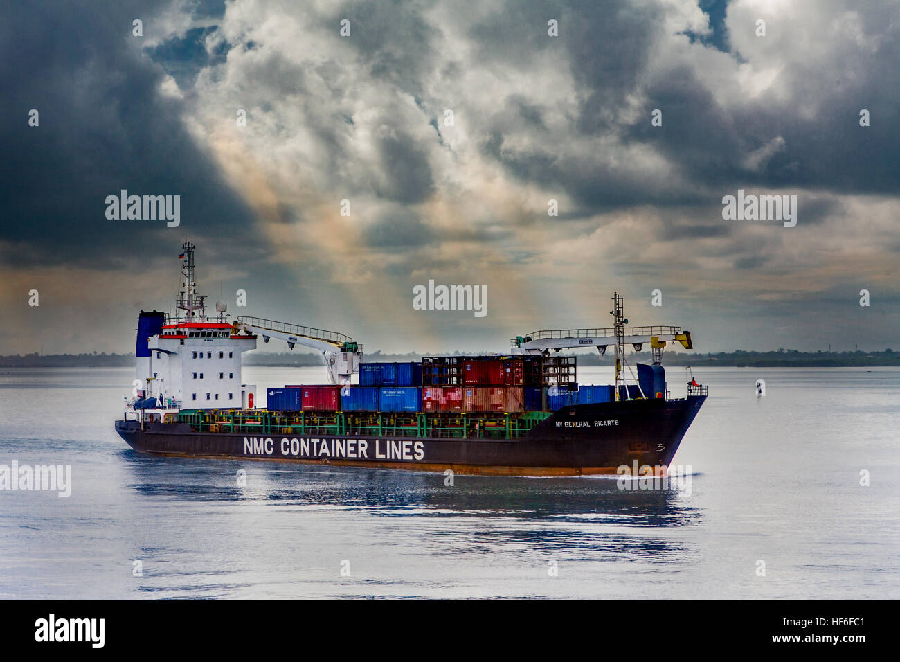 Un contenitore di carico nave cargo in mare si fa strada al di fuori del porto di Cebu nelle Filippine. Foto Stock
